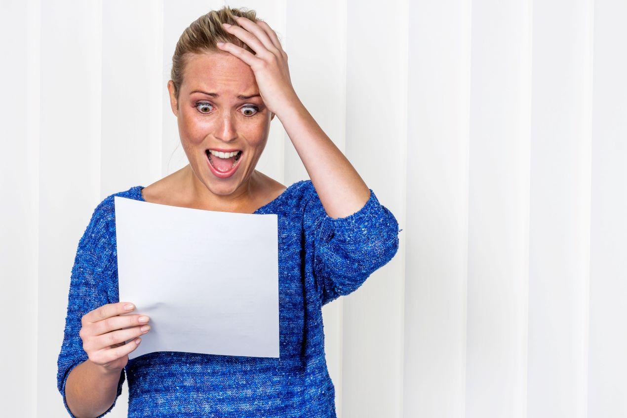 Eine schockierte Frau hält ein Dokument in der Hand, symbolisch für die Folgen von rechtlichem Halbwissen. Unterstützt durch die Kanzlei Ra-Hartung.